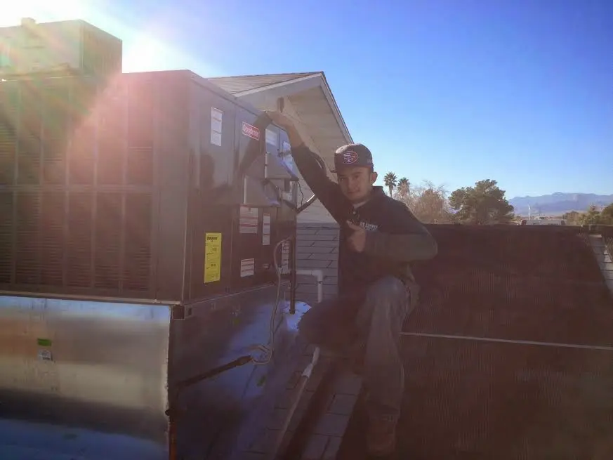 HVAC technician performing Heat Pump Repair on a rooftop unit in Watertown